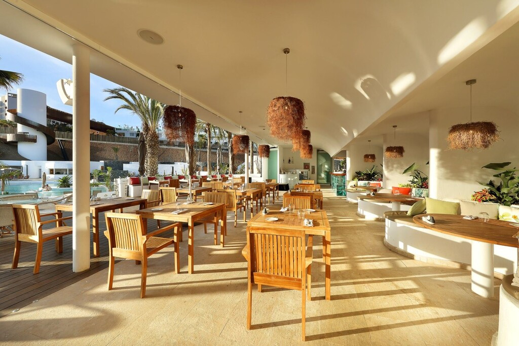 Openluchtrestaurant met houten stoelen en uitzicht op het zwembad op Tenerife.