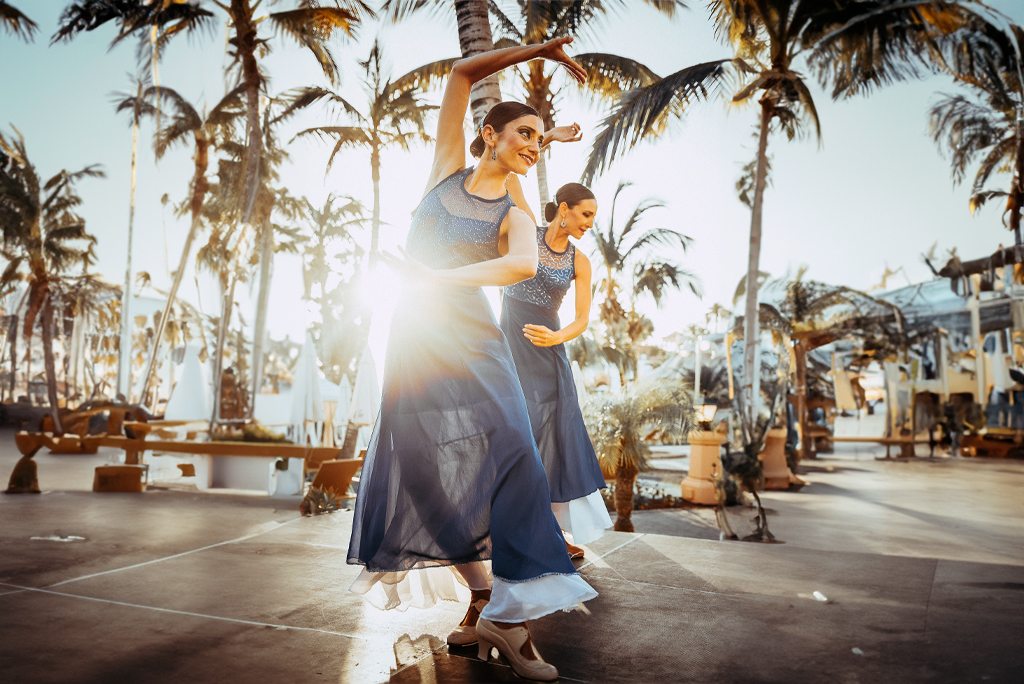 Dansers die optreden tussen palmbomen bij zonsondergang op Tenerife.