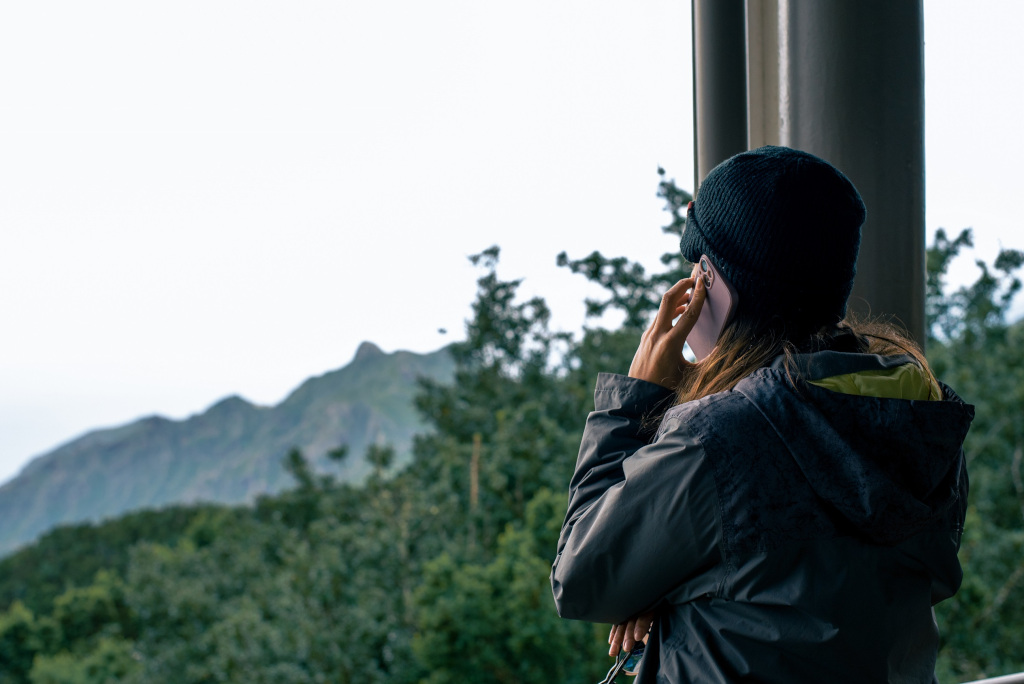 Persoon aan de telefoon met een bergachtig landschap op Tenerife op de achtergrond.