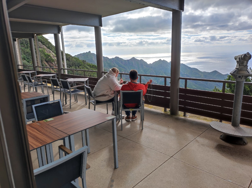 Mensen die op een terras zitten met uitzicht op de bergen en de zee op Tenerife.