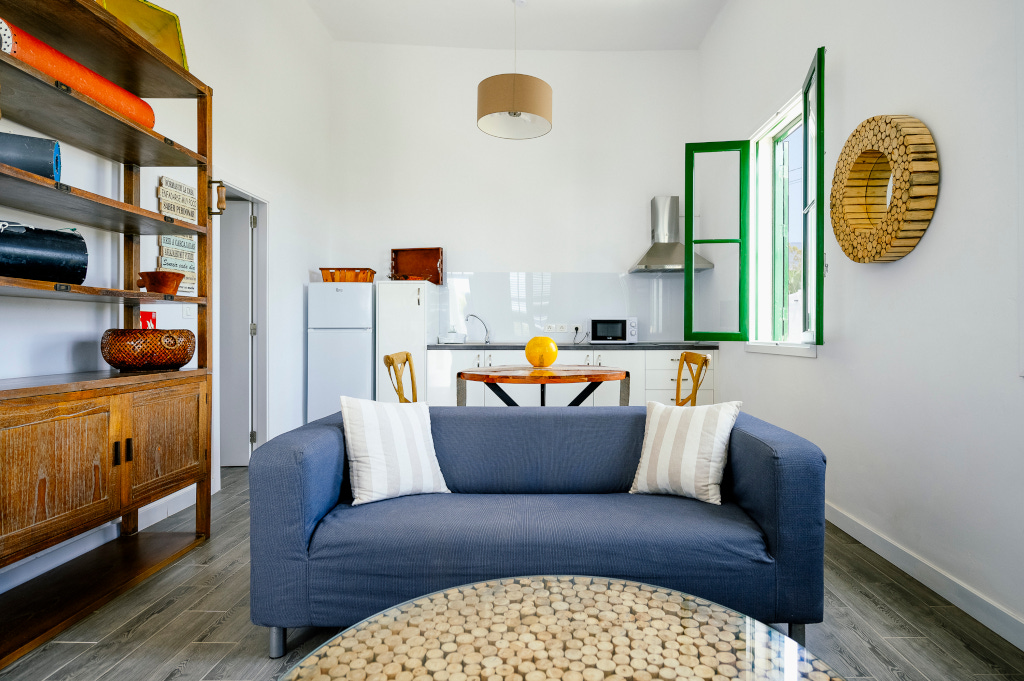 Woonkamer met open keuken, blauwe bank, salontafel en groen raam op Tenerife.