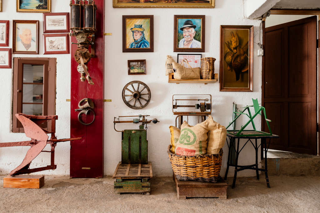 Antieke voorwerpen hangen aan een muur, waaronder schilderijen, een weegschaal en zakken op Tenerife.