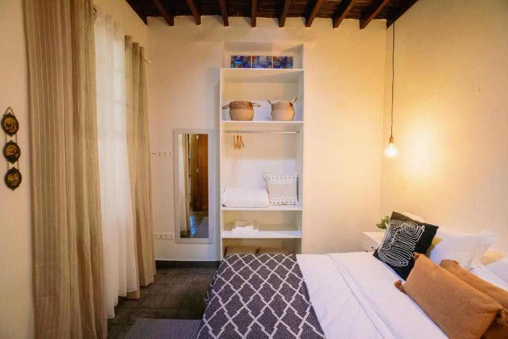 Knusse kamer op Tenerife met bed, plank met handdoeken en eenvoudige decoratie.