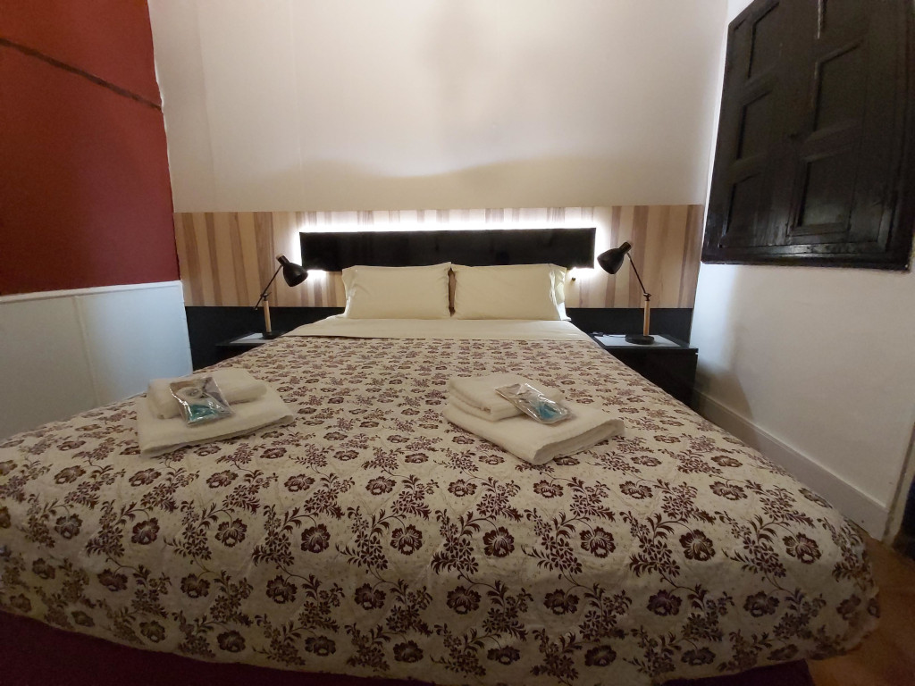 Tweepersoonsbed met bloemige deksprei, lampen en handdoeken in een hotelkamer op Tenerife.