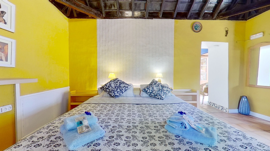 Kamer met tweepersoonsbed en gele muren op Tenerife, met handdoeken op het bed.