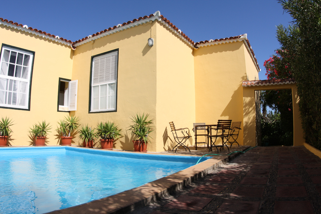 Zwembad en terras met stoelen naast een geel huis op Tenerife.