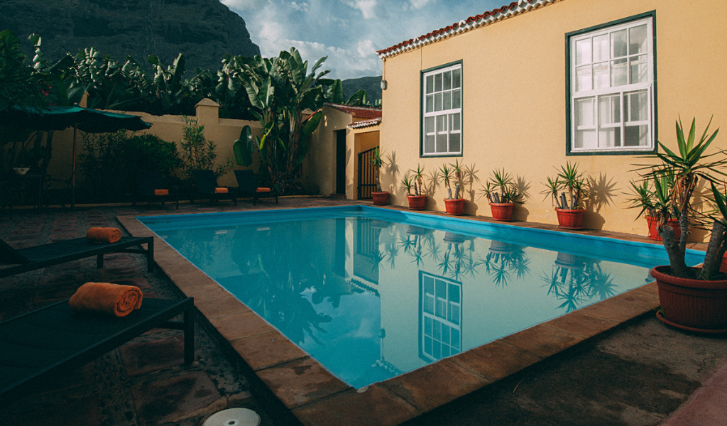 Zwembad omringd door planten in een binnenplaats met ligstoelen op Tenerife.