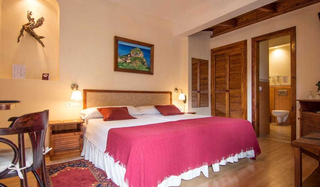 Dubbele kamer met badkamer in een hotel op Tenerife, met een groot bed en warme decoratie.