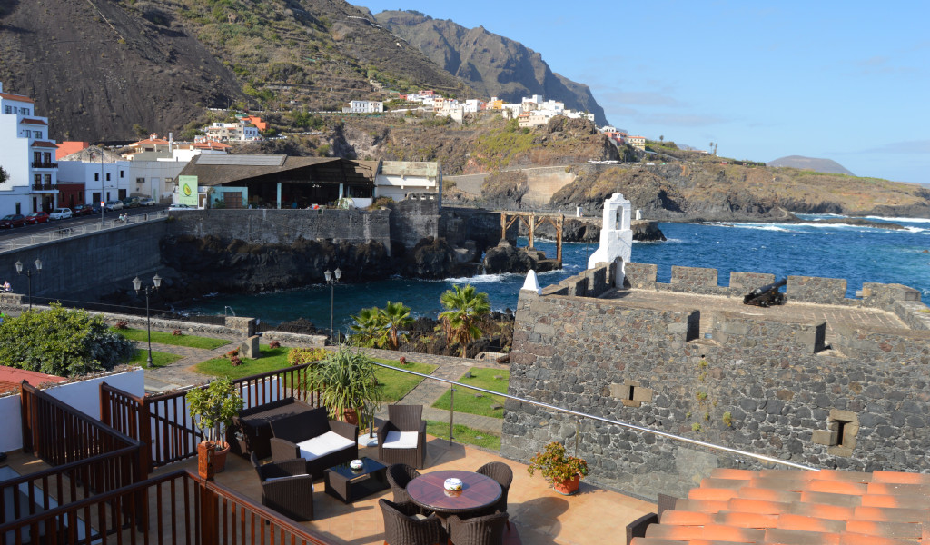 Kustzicht op Garachico, Tenerife, met huizen, zee en bergen op de achtergrond.