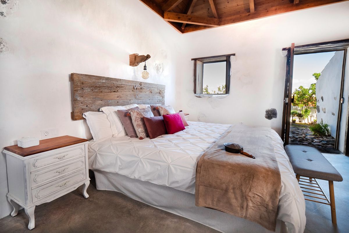 Bed met houten hoofdeinde en open raam in de kamer van Tenerife.