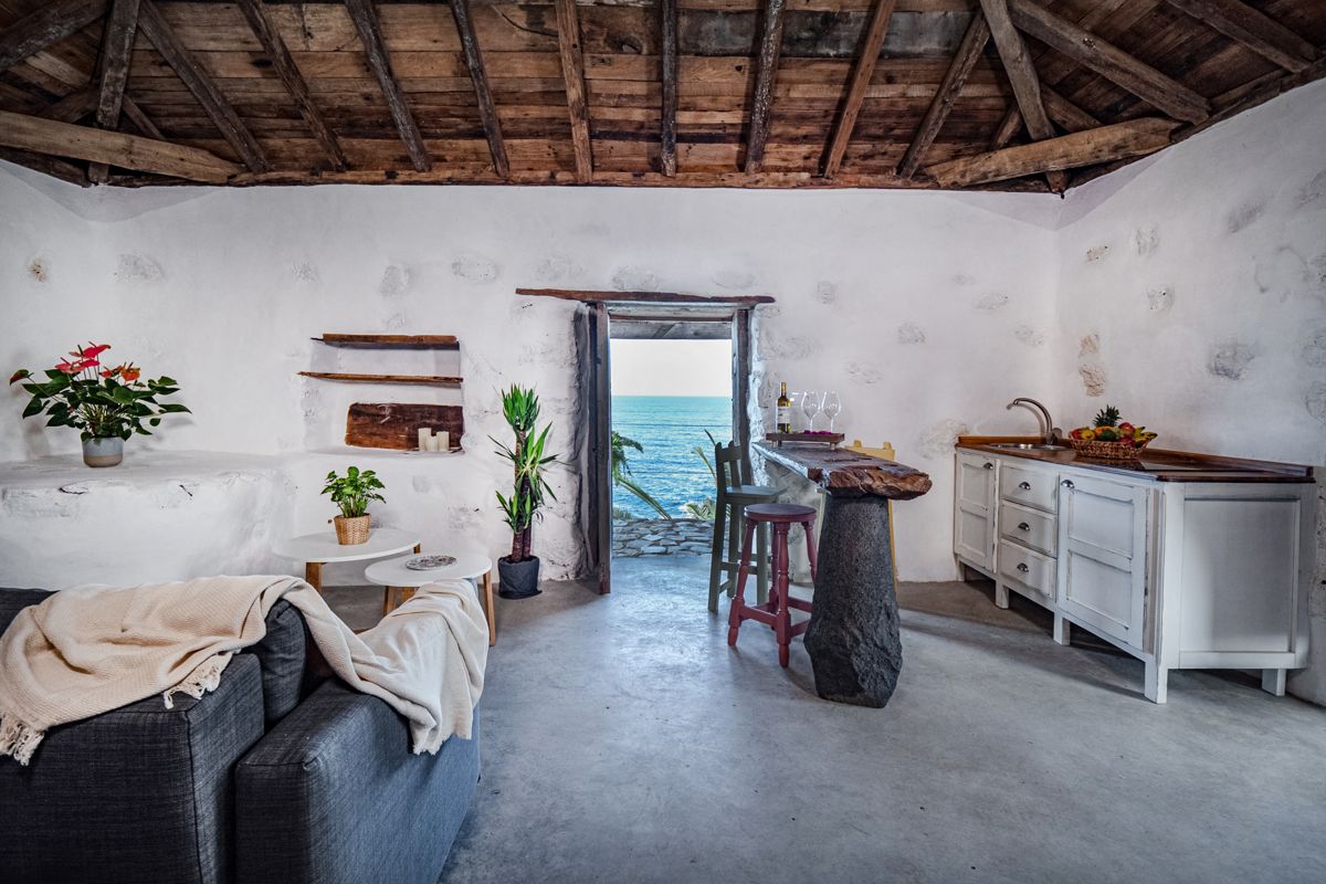 Rustieke woonkamer op Tenerife met houten plafond en zeezicht door de deur.