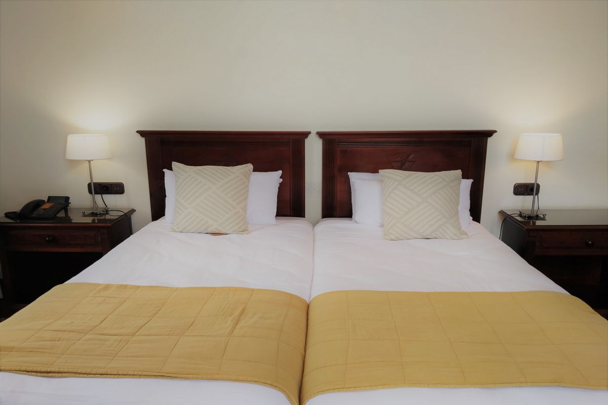 Tweepersoonsbed met houten hoofdeinde en nachtkastjes in een hotel op Tenerife.
