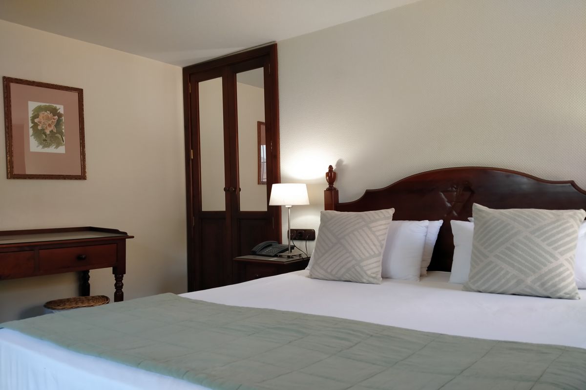 Tweepersoonsbed met kussens en lamp in een hotelkamer op Tenerife.