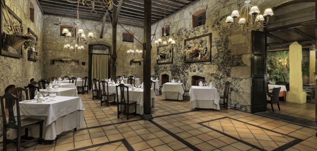 Restaurant op Tenerife met kaptafels en hangende lampjes in een rustieke ruimte.