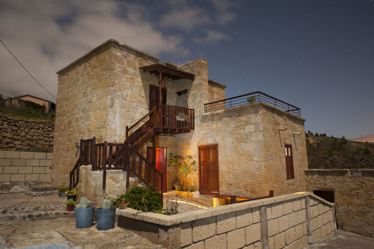 Stenen huis verlicht 's nachts in Chio, Tenerife, met sterrenhemel.