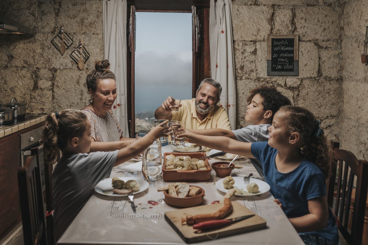 Familie proost in een keuken met uitzicht op Tenerife, herzlich willkommen zu meinem Haus Las Vegas op het schoolbord.