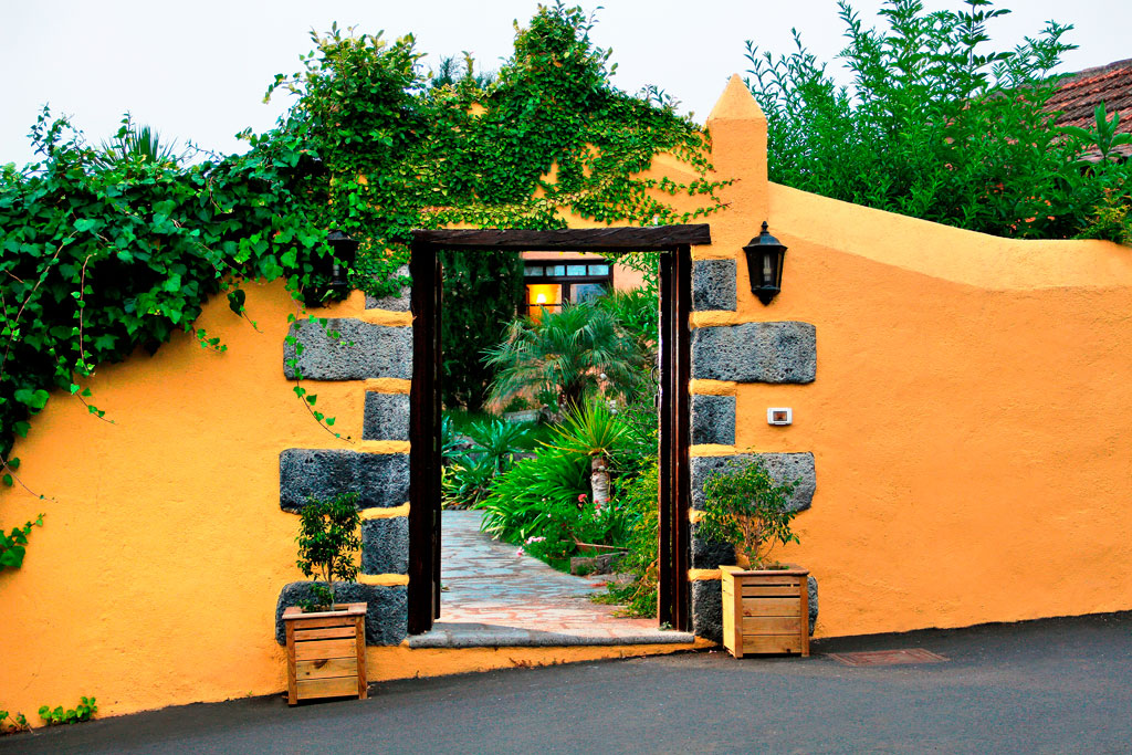 Ingang met planten en een sierlijke gele muur, typisch voor Tenerife.