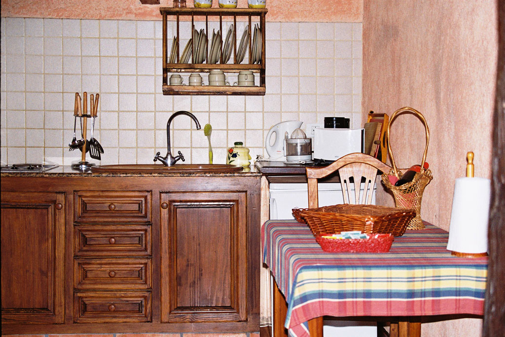 Rustieke keuken met houten meubels op Tenerife. Tafel met geruit tafelkleed en servies.