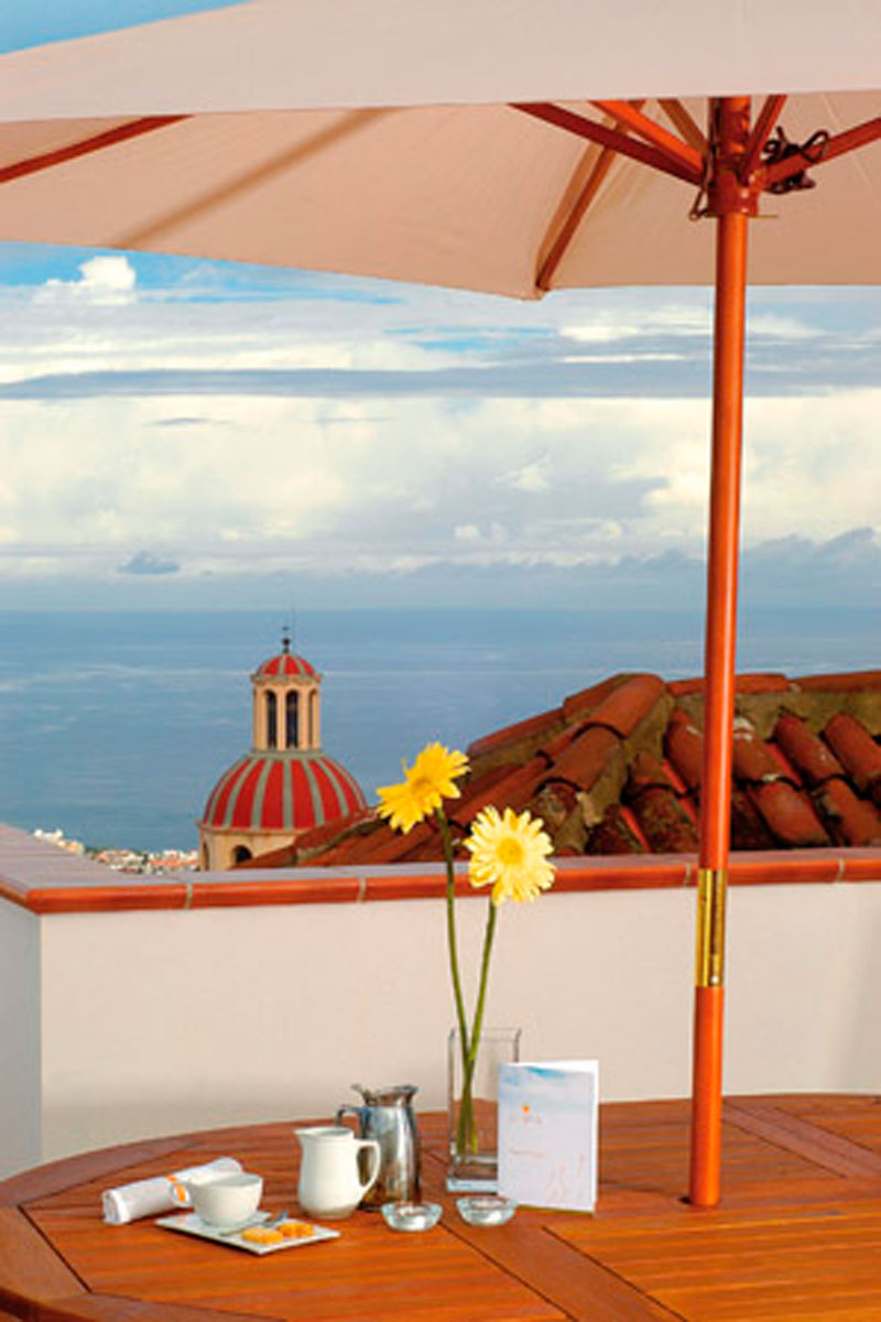 Tafel met koffiekan, bloemen en menu, zeezicht en koepel op Tenerife.