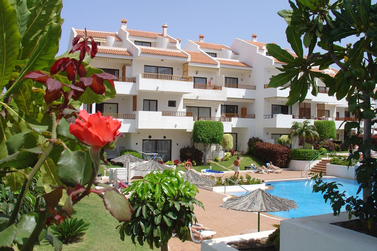 Appartementencomplex met zwembad en tuinen op Tenerife, omgeven door natuur.
