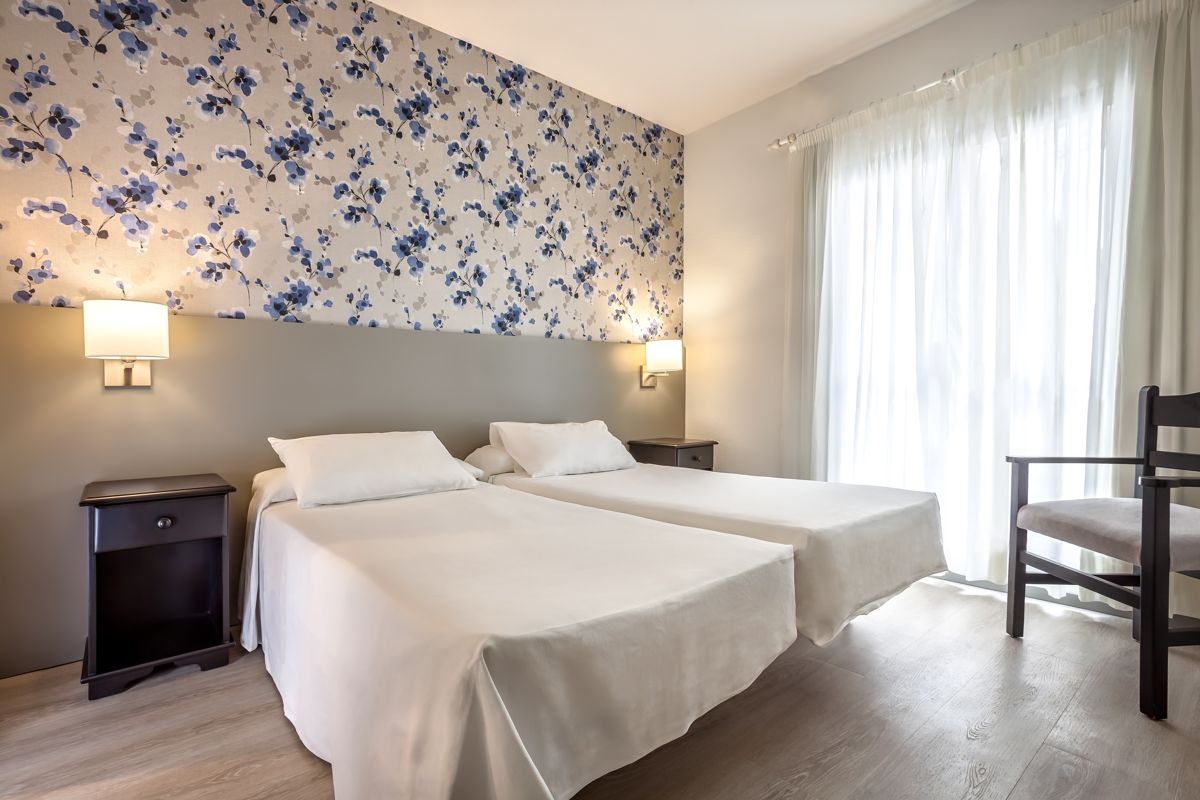 Twee eenpersoonsbedden in een lichte kamer met bloemenbehang op Tenerife.