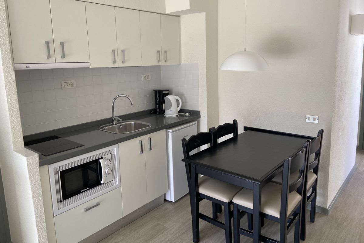 Kleine keuken met tafel, stoelen, magnetron en gootsteen in een appartement op Tenerife.