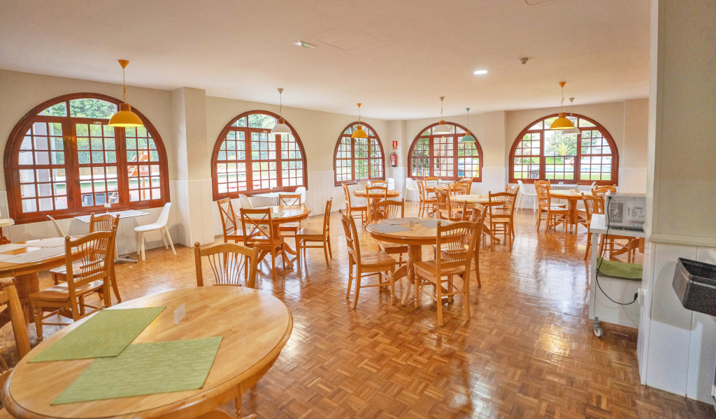 Eetkamer met houten tafels en stoelen naast gebogen ramen op Tenerife.