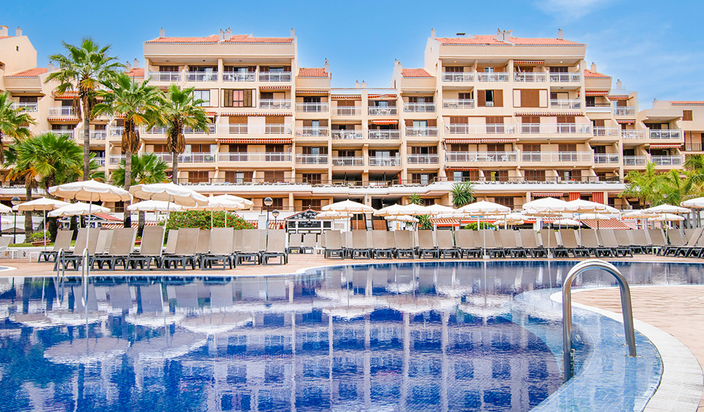 Zwembad en hotel met palmbomen in Los Cristianos, Tenerife.