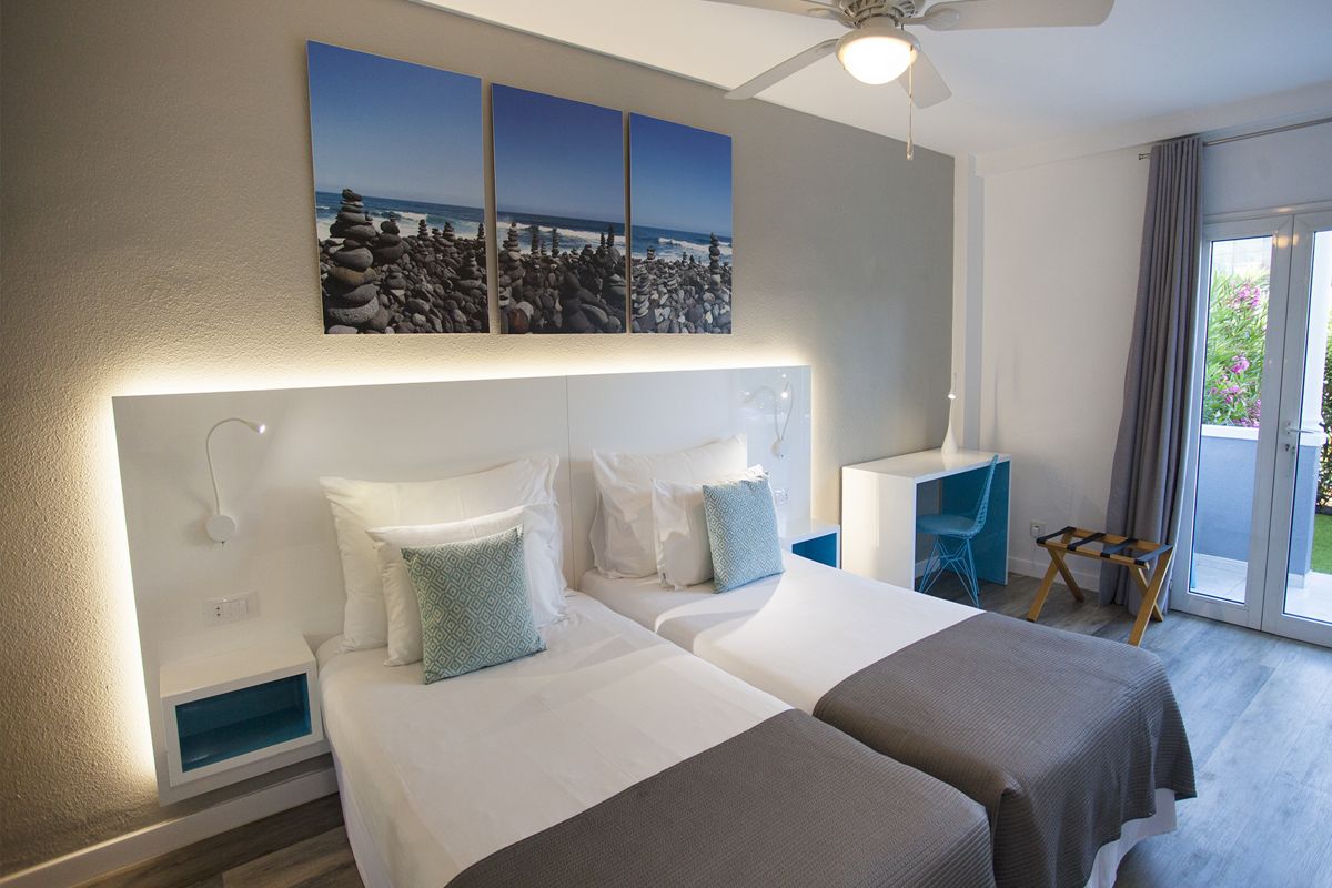 Moderne slaapkamer met eenpersoonsbedden en oceaanschilderingen op Tenerife.