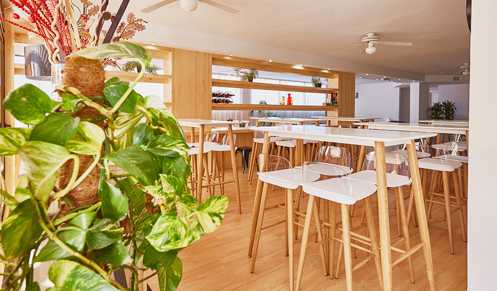 Restaurant met hoge houten tafels en planten binnen, Tenerife.