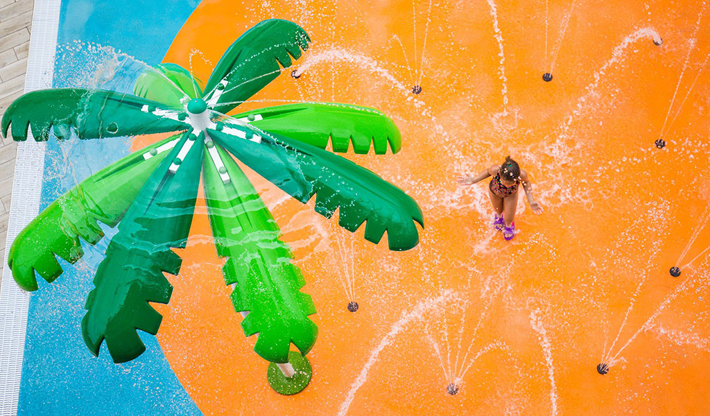 Klein meisje dat speelt in een waterpark met waterstraal op Tenerife.