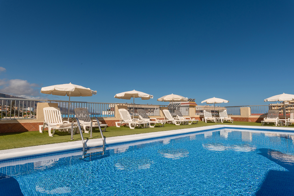 Zwembad met ligstoelen en parasols in een hotel op Tenerife.