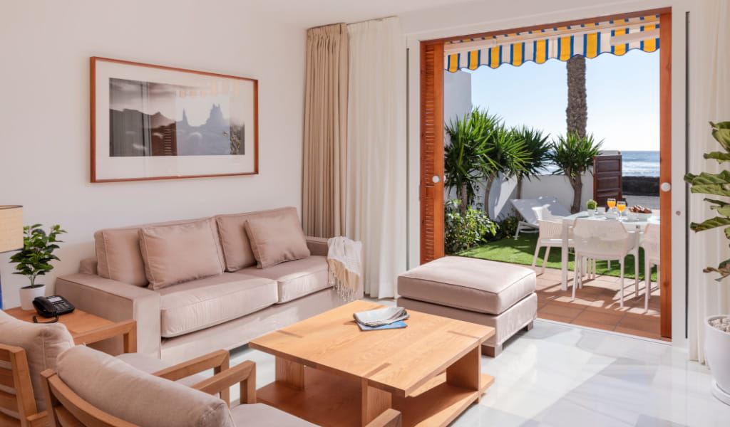 Woonkamer met toegang tot de tuin, modern meubilair en zeezicht op Tenerife.
