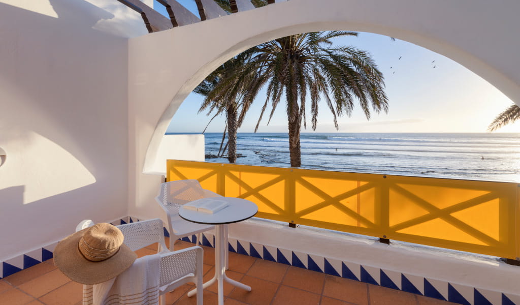 Terras met tafel en stoelen gericht op zee op Tenerife, uitzicht op palmbomen en skyline.
