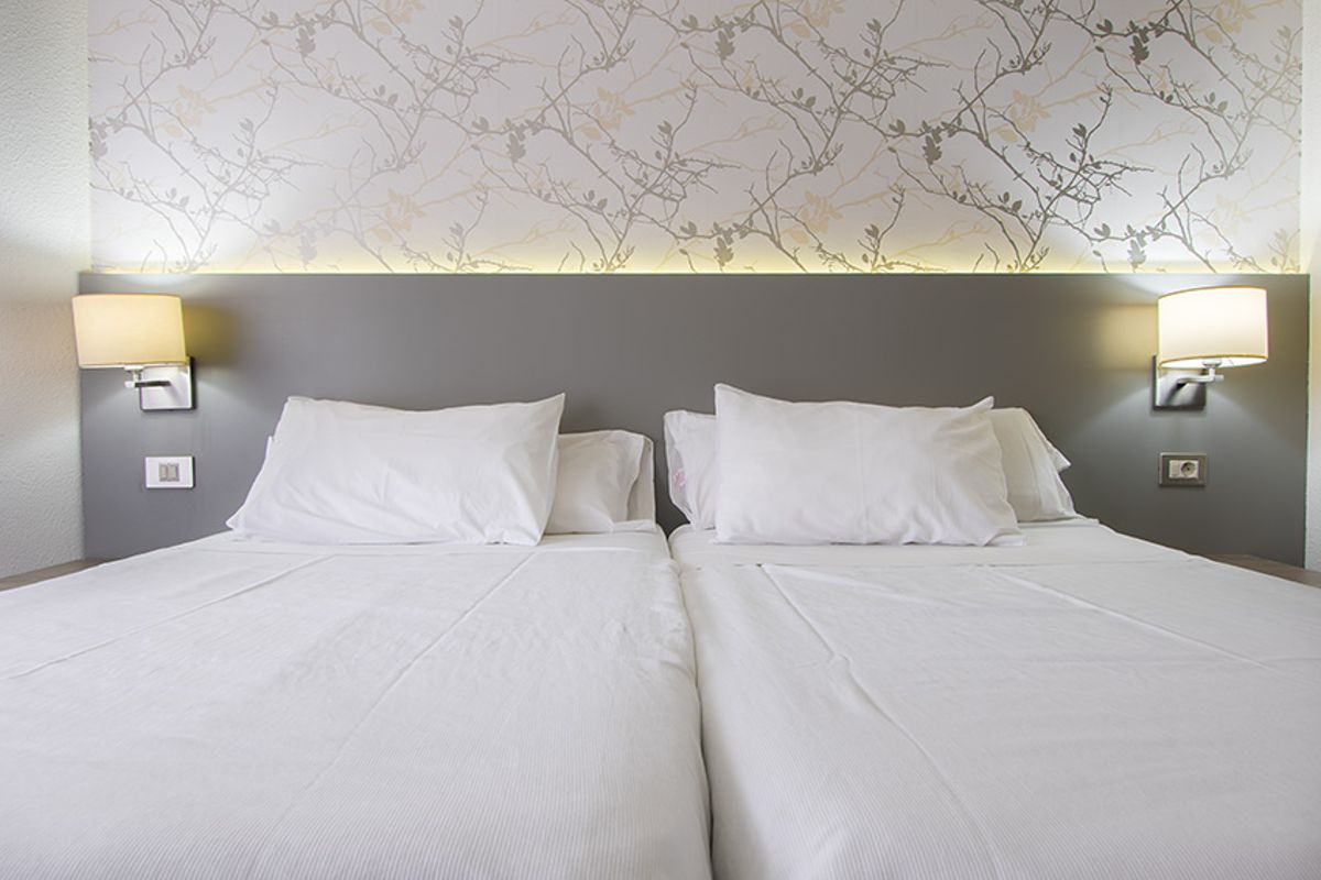 Dubbele bedden met grijs hoofdeinde en lampen in een hotel op Tenerife.