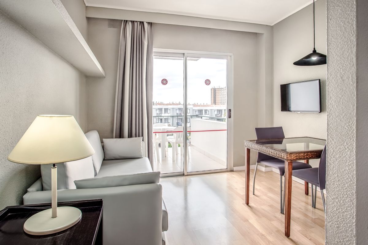 Lichte woonkamer met bank, tv, eettafel en balkon op Tenerife.