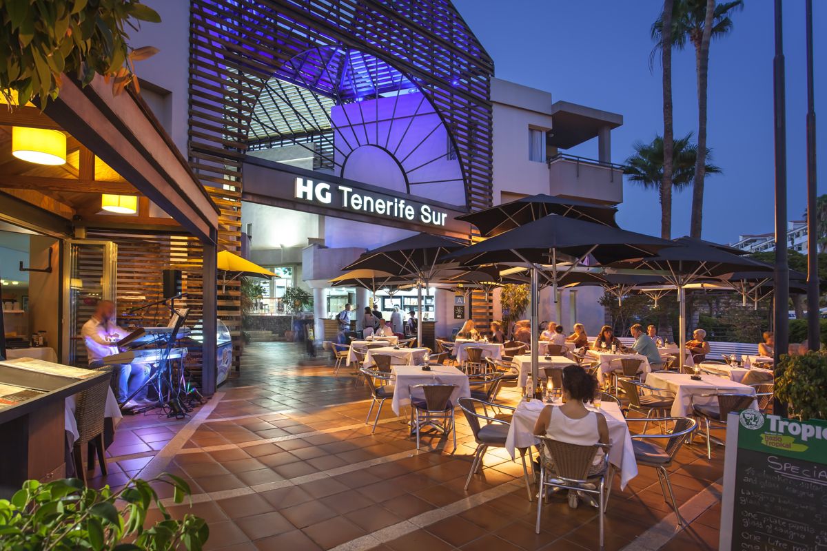 Restaurantterras bij HG Tenerife South in de avond, met eters die buiten dineren.
