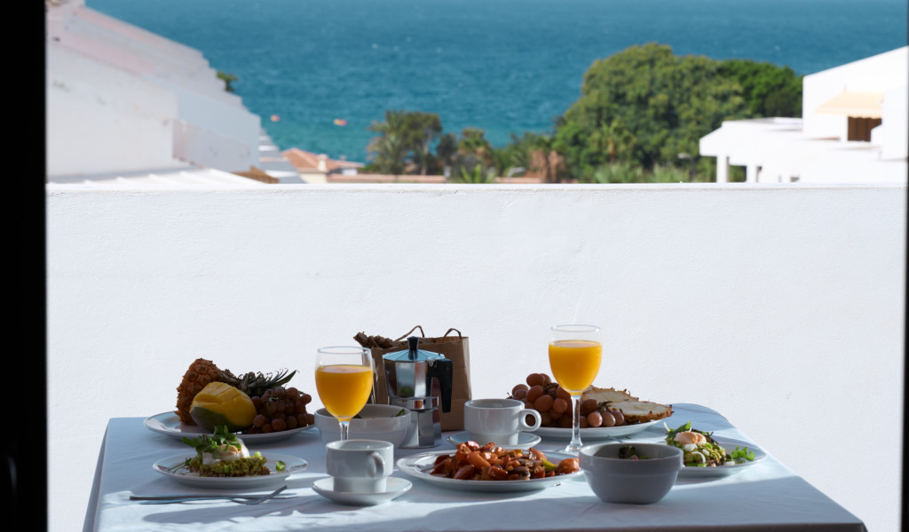 Ontbijt met uitzicht op zee op een balkon op Tenerife, met fruit en sinaasappelsap.