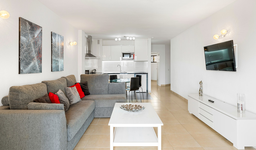 Moderne woonkamer op Tenerife met een grijze bank en geïntegreerde keuken.