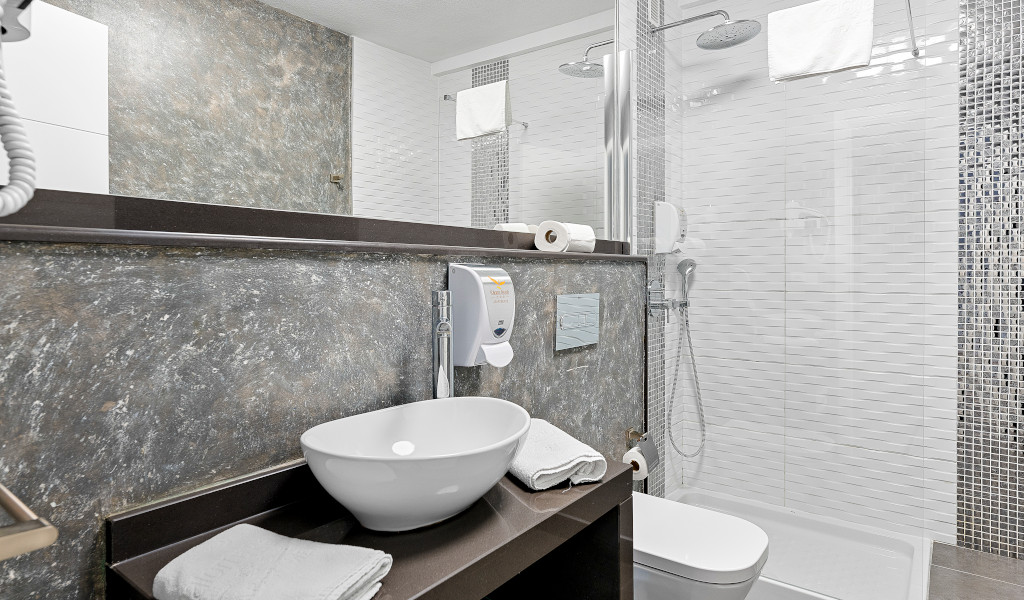 Moderne badkamer met wastafel, spiegel, douche en handdoeken in het hotel van Tenerife.