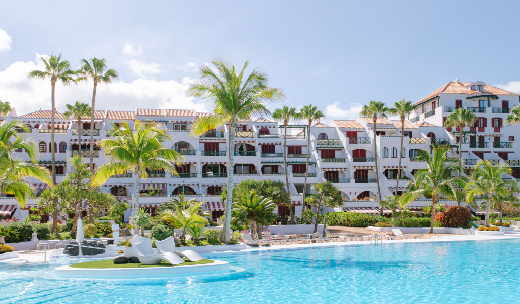 Zwembad voor het hotel, omringd door palmbomen op een zonnige dag op Tenerife.