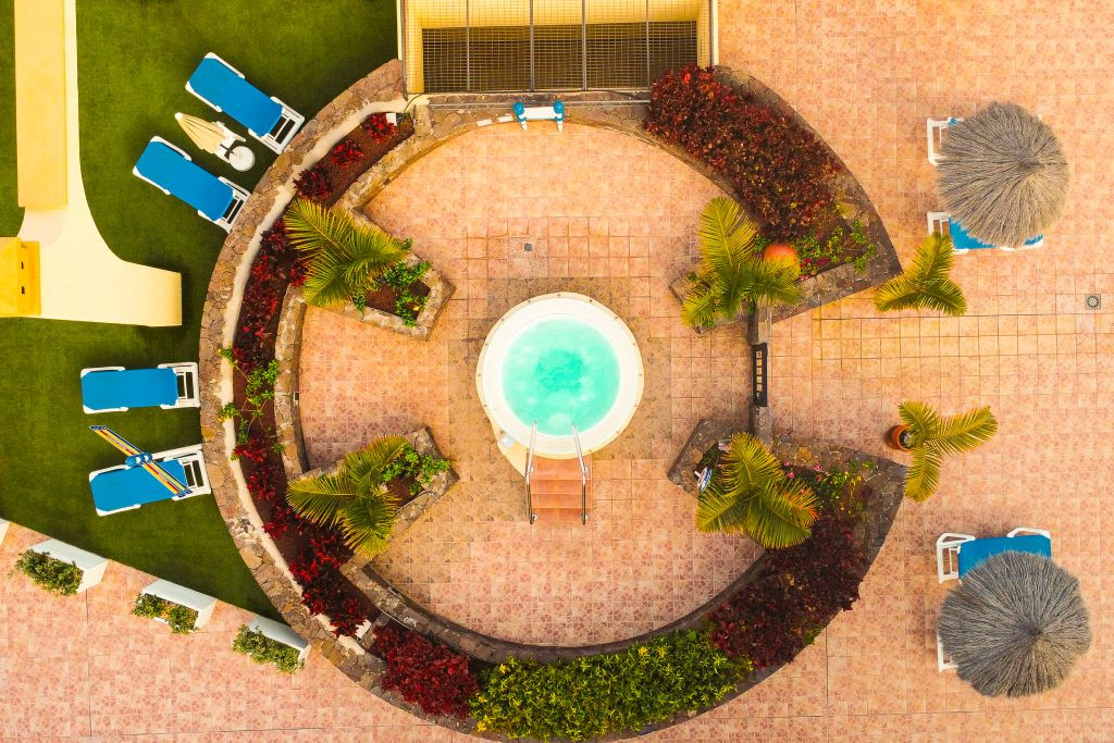 Luchtfoto van een rond zwembad omringd door ligstoelen en palmbomen op Tenerife.
