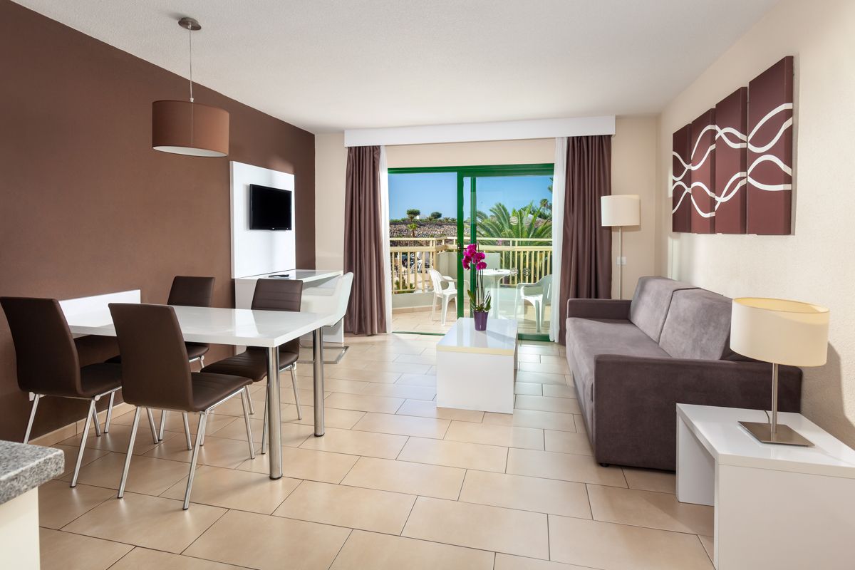 Woonkamer met modern meubilair en balkon met uitzicht op een palmboom op Tenerife.