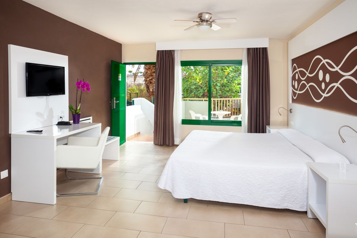 Hotelkamer met tweepersoonsbed, bureau en uitzicht op de tuin op Tenerife.