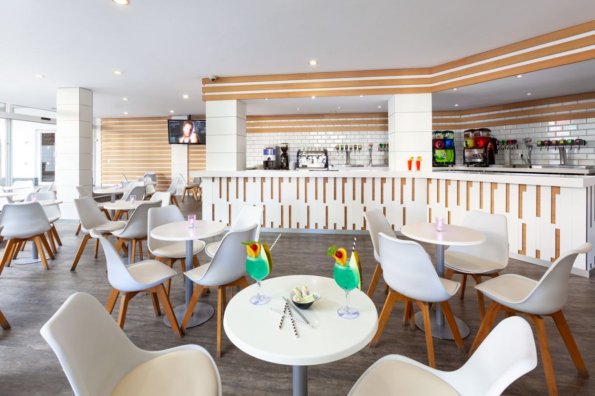 Moderne bar met witte stoelen en ronde tafels in Santa Cruz de Tenerife.