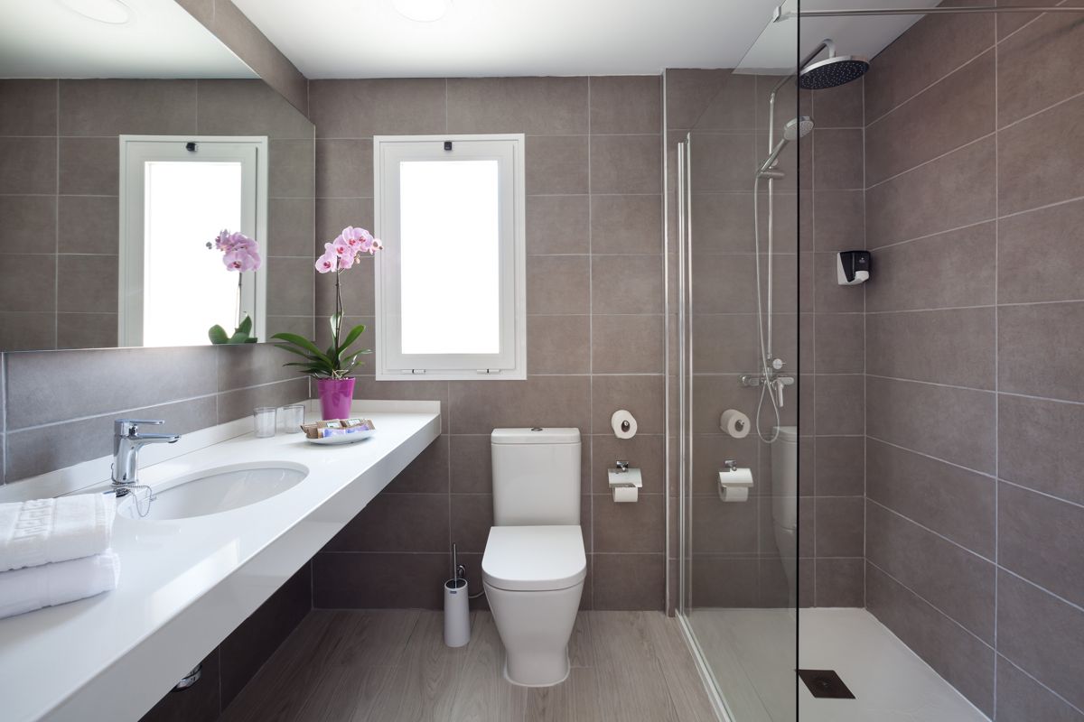 Moderne badkamer met douche, wastafel, toilet en raam in het appartement op Tenerife.