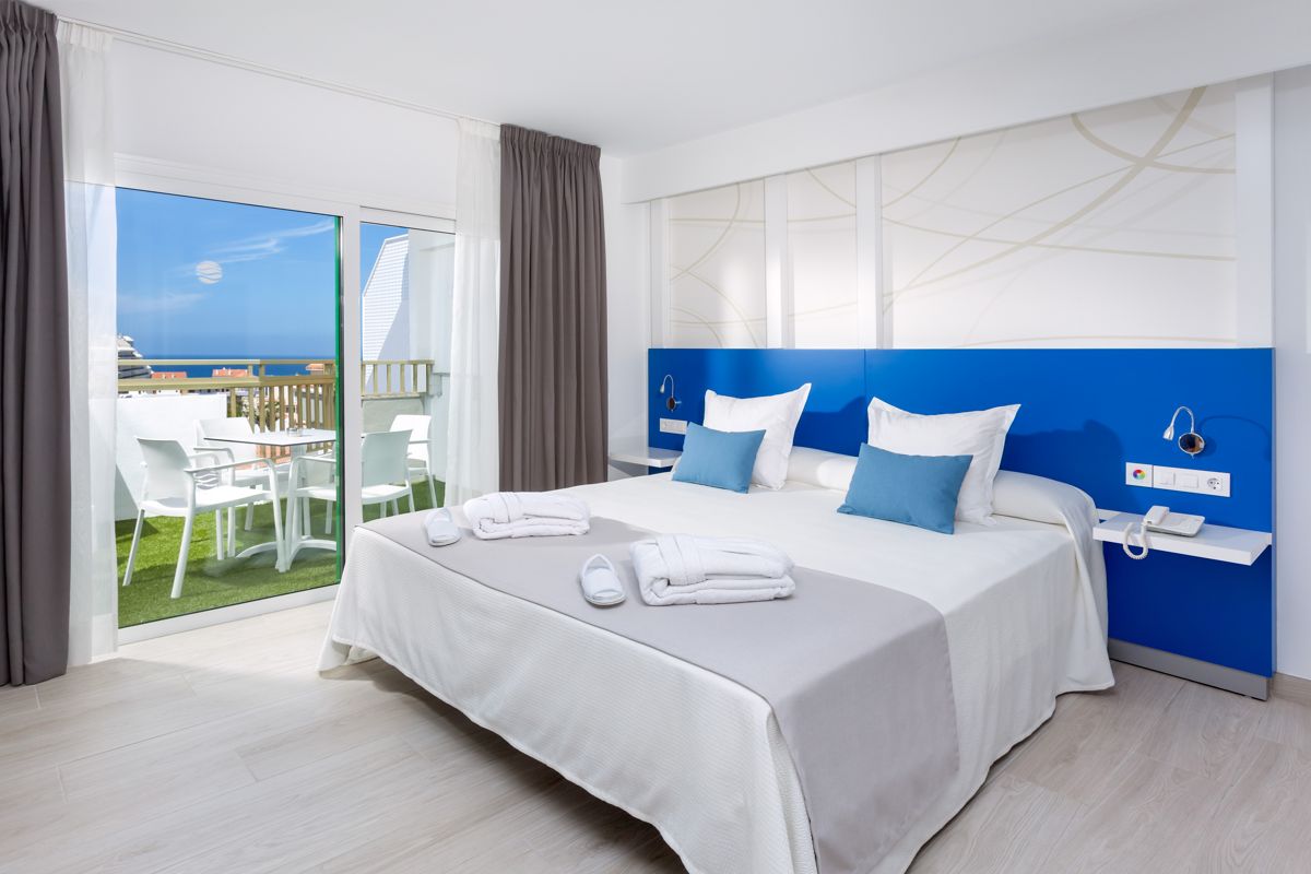 Hotelkamer op Tenerife met tweepersoonsbed, terras en uitzicht op zee.