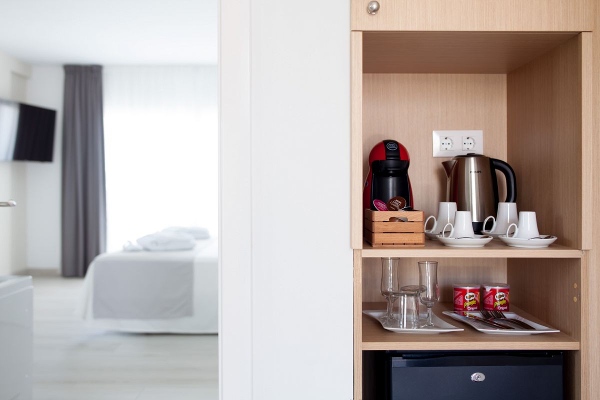 Plank met koffiezetapparaat, kopjes en waterkoker in een hotelkamer op Tenerife.