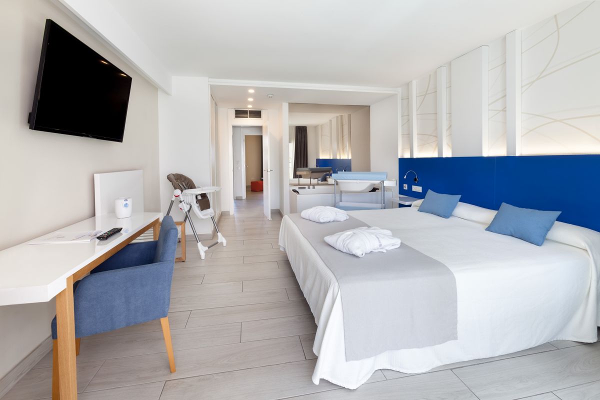 Hotelkamer op Tenerife met een tweepersoonsbed, bureau en tv aan de muur.