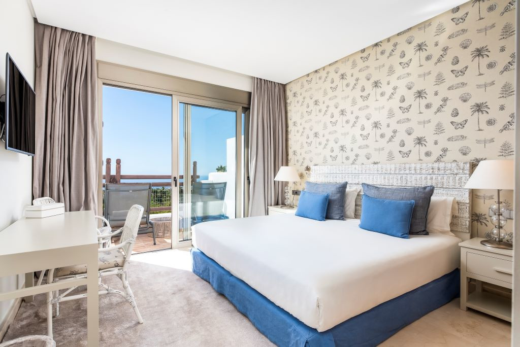 Kamer met tweepersoonsbed, blauwe kussens en balkon met uitzicht op zee op Tenerife.